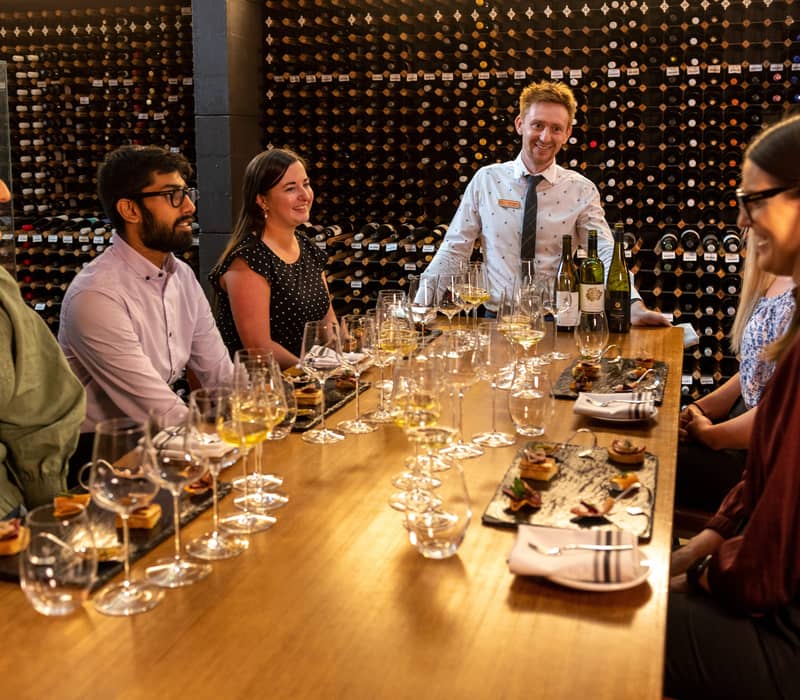 Guests seated at a long wooden table for a wine tasting at the National Wine Centre of Australia.