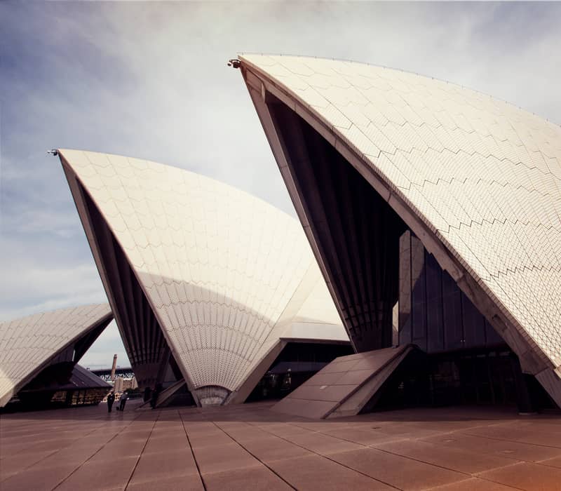 Close-up architectural shot of the white tiled sails of the Sydney Opera House under a bright sky.