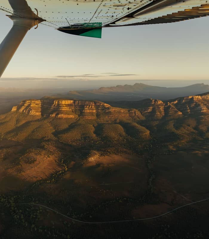 View from a plane wing overlooking the massive mountain crater of Wilpena Pound at sunrise.
