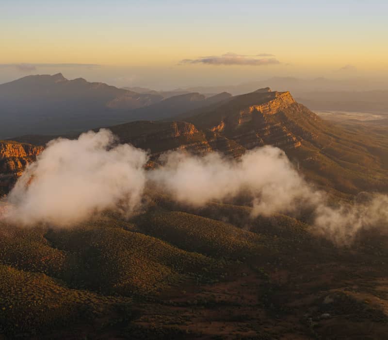 Low clouds drifting through the valleys of the Flinders Ranges mountains during golden hour.