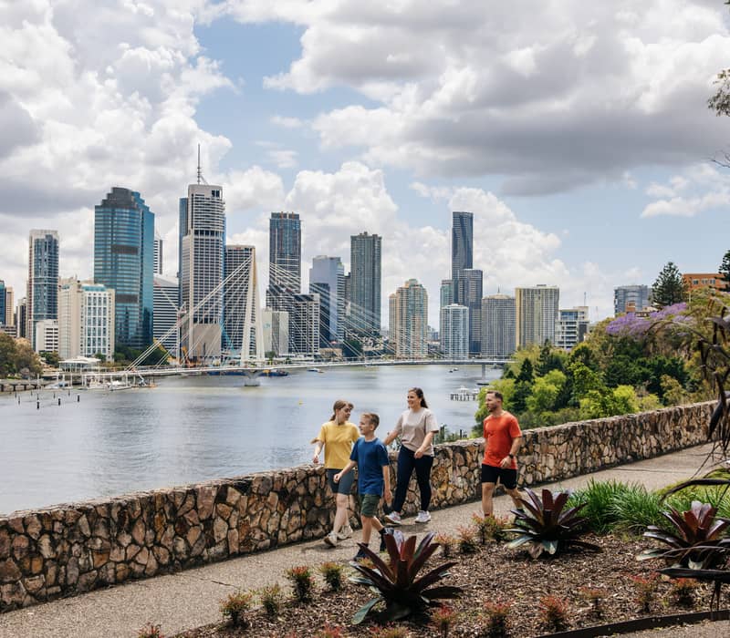 A family walks under the purple bougainvillea flower arches at South Bank Parklands in Brisbane.