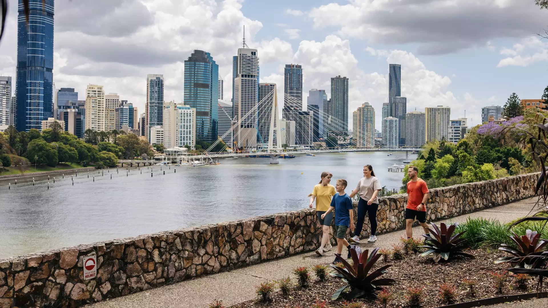 A family walks under the purple bougainvillea flower arches at South Bank Parklands in Brisbane.