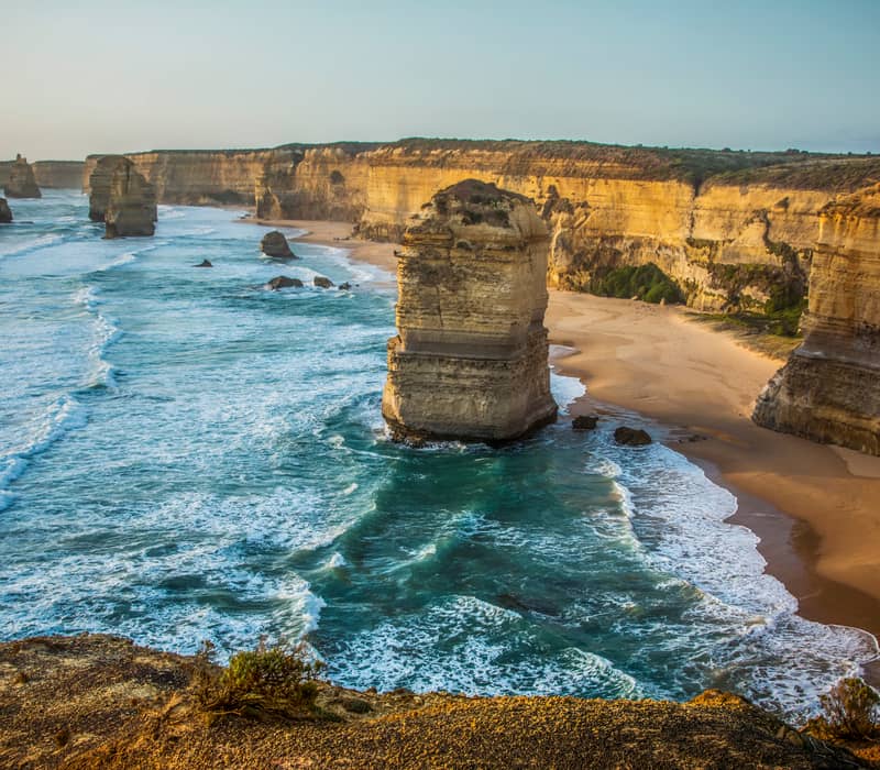Scenic view of limestone rock stacks in the ocean along a high cliff coastline.