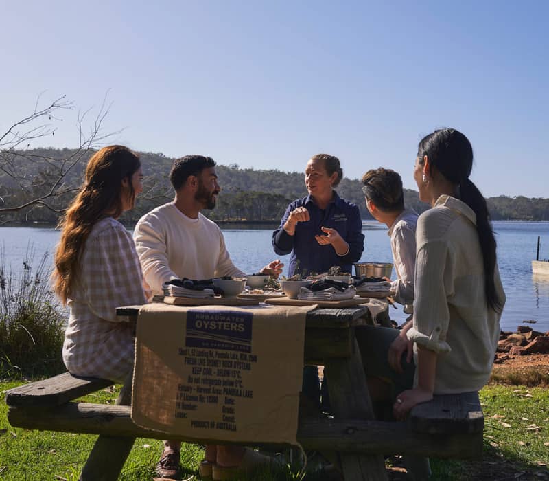 A local expert teaching guests how to shuck oysters during a Navigate Expeditions tour at Pambula Lake.