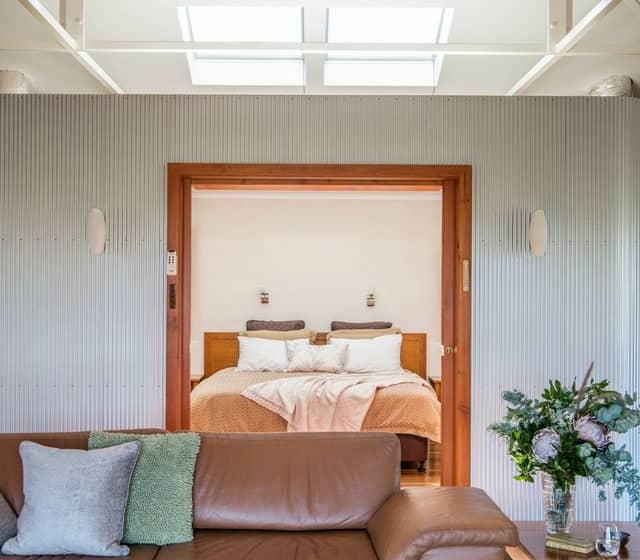 Modern interior of a luxury eco-villa at Rawnsley Park Station with a brown leather sofa and vaulted ceilings.