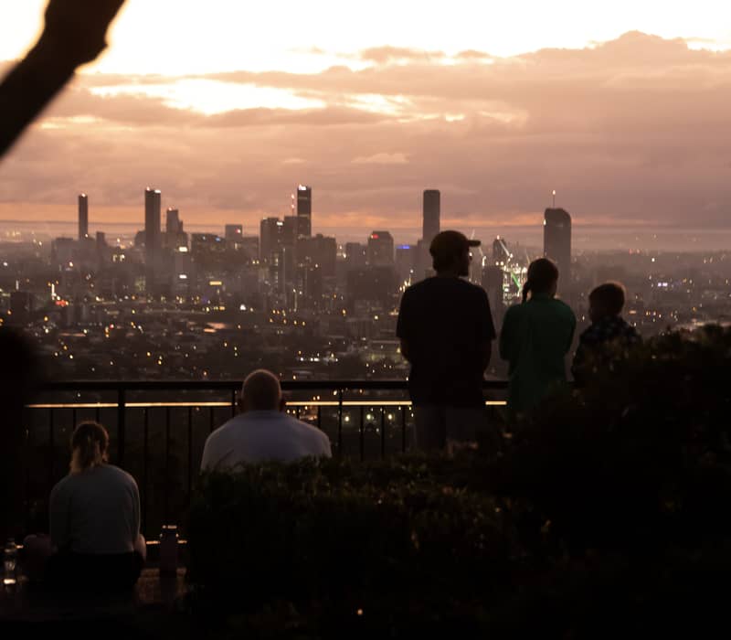 Silhouette of a family looking out over the Brisbane city skyline under a twilight sky from Mount Coot-tha.