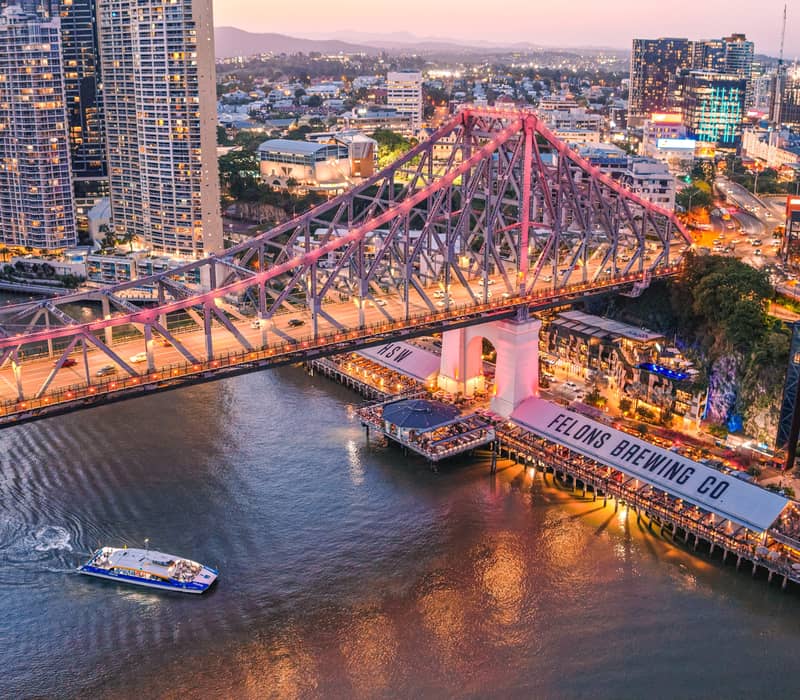 Night aerial of the Story Bridge lit up over the Felons Brewing Co restaurant and brewery precinct.