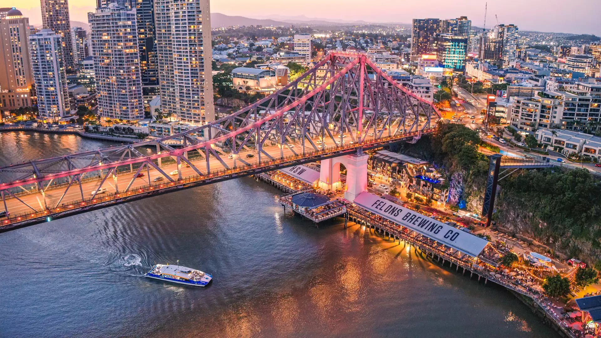 Night aerial of the Story Bridge lit up over the Felons Brewing Co restaurant and brewery precinct.