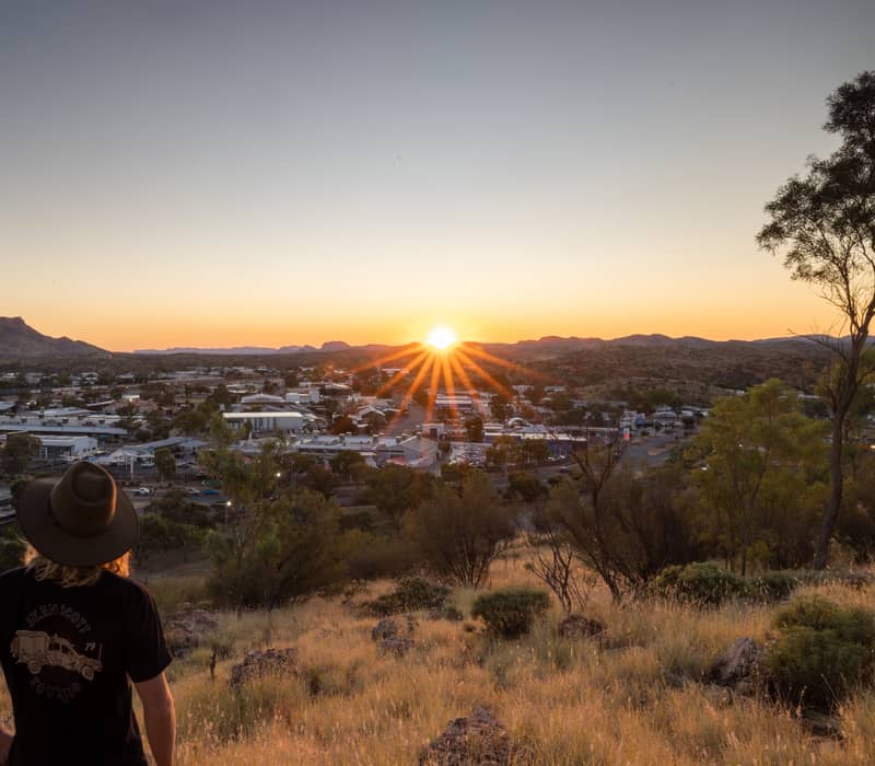 A person in a hat viewing the sunset over Alice Springs from the top of Anzac Hill.