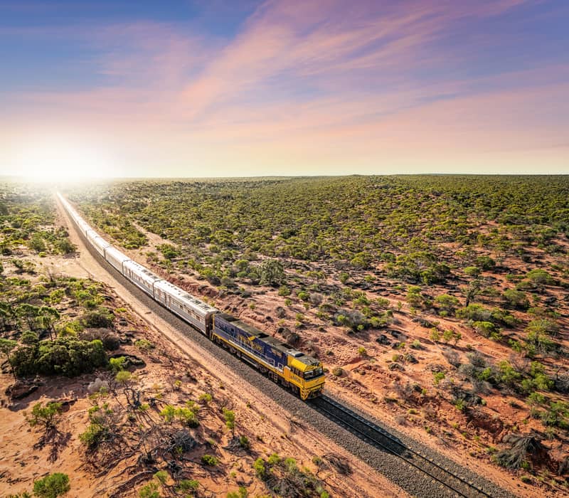 A cinematic aerial "hero shot" of the iconic Indian Pacific train winding through Ooldea SA.