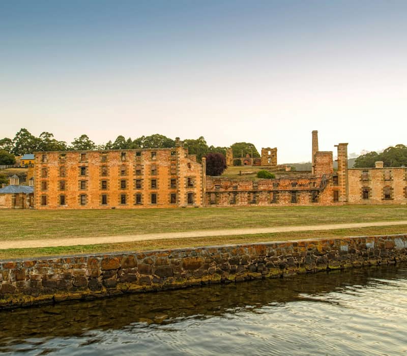 Ruins of brick buildings at Port Arthur in Tasmania near water under a clear sky