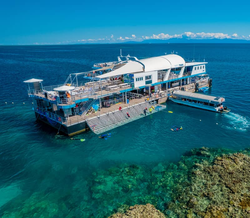 Aerial view of the Reef Magic activity pontoon on the Great Barrier Reef with a transfer catamaran docked alongside.