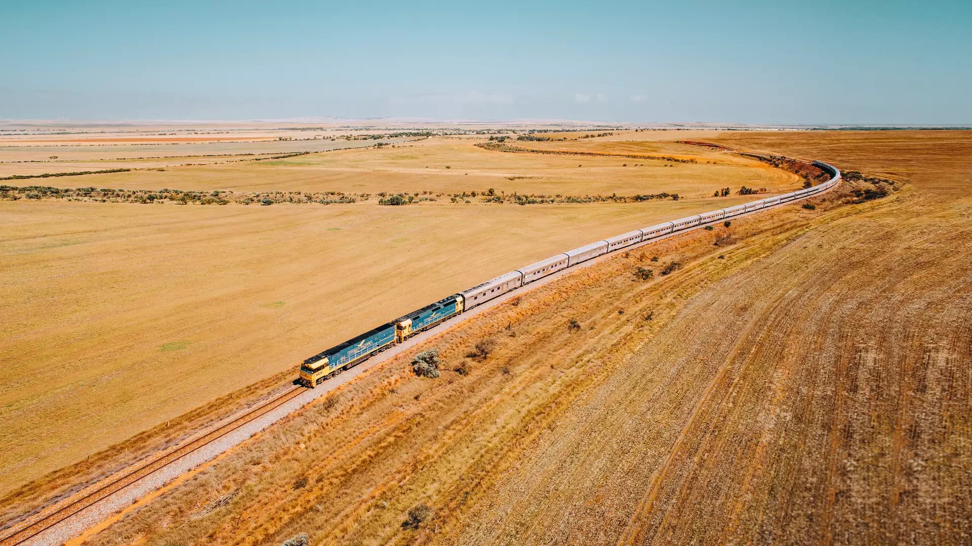 A cinematic aerial "hero shot" of the iconic Indian Pacific train winding through Clare Valley, SA. 