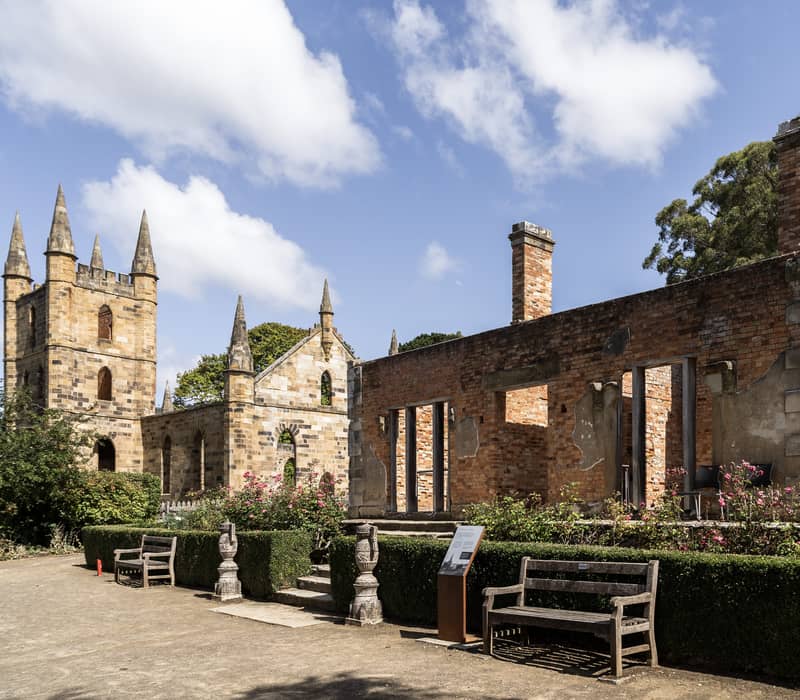 The brick ruins of the Government Cottage stand beside a manicured heritage garden at Port Arthur. 