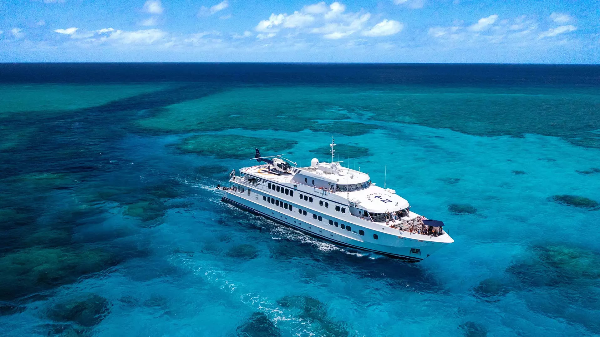 The 50-metre flagship vessel True North navigates the crystal-clear turquoise waters of the Great Barrier Reef. 
