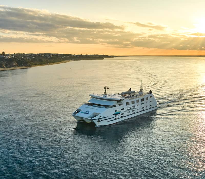 High angle view of a large ferry boat on the water near the Victorian coastline at sunset.