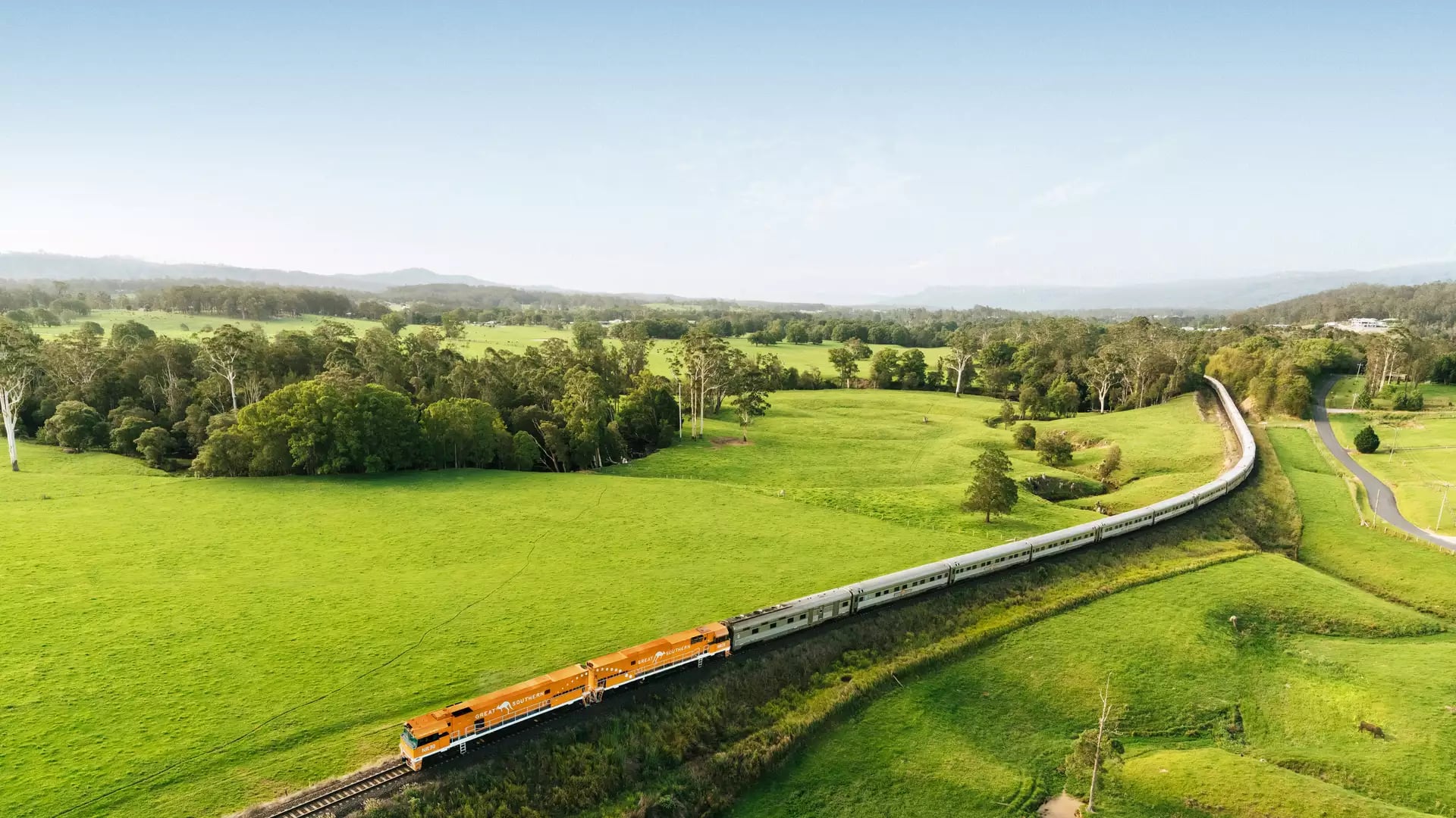 The Great Southern passenger train traveling through lush green meadows in rural New South Wales.
