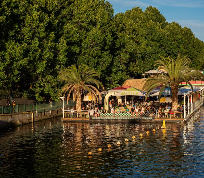 People sitting at a floating bar and restaurant on the Yarra River in Melbourne CBD.