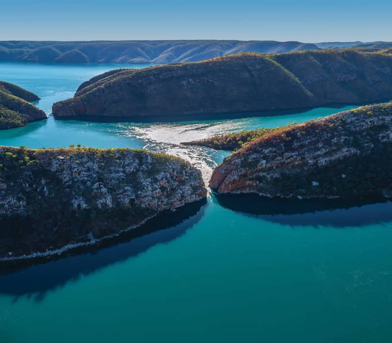 Aerial view of turquoise water rushing through narrow rock gaps at Horizontal Falls in the Kimberley.