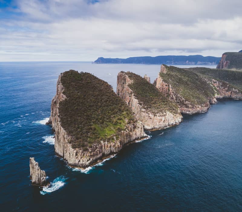 Aerial view of a narrow, rocky coastal peninsula surrounded by deep blue ocean water.