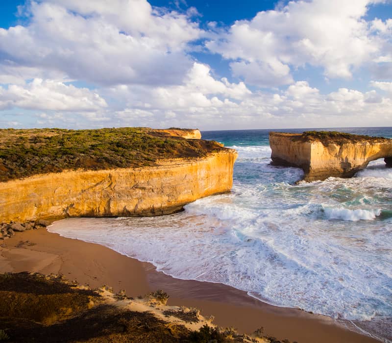 Scenic coastal view of the London Arch rock formation and a secluded beach on the Great Ocean Road in Victoria.