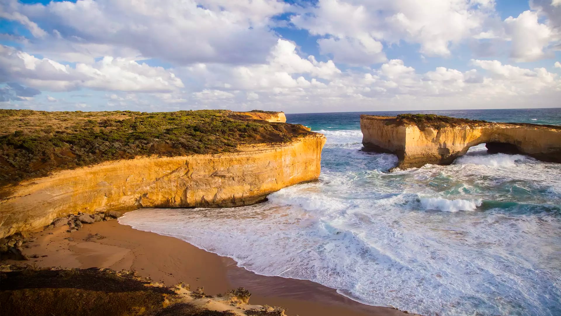 Scenic coastal view of the London Arch rock formation and a secluded beach on the Great Ocean Road in Victoria.