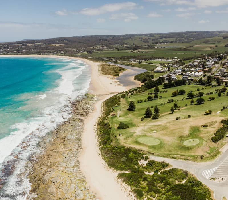 Aerial perspective of Apollo Bay beach, town, and golf course along the Victorian coast.