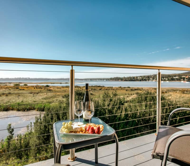 : A gourmet grazing platter with local Tasmanian wine served on a private balcony at the Panorama Hotel St Helens, offering elevated views over the township and the blue waters of Georges Bay..