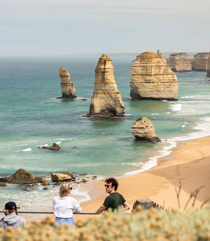 Tourists looking out over the Twelve Apostles limestone stacks and turquoise ocean on the Great Ocean Road, Victoria.