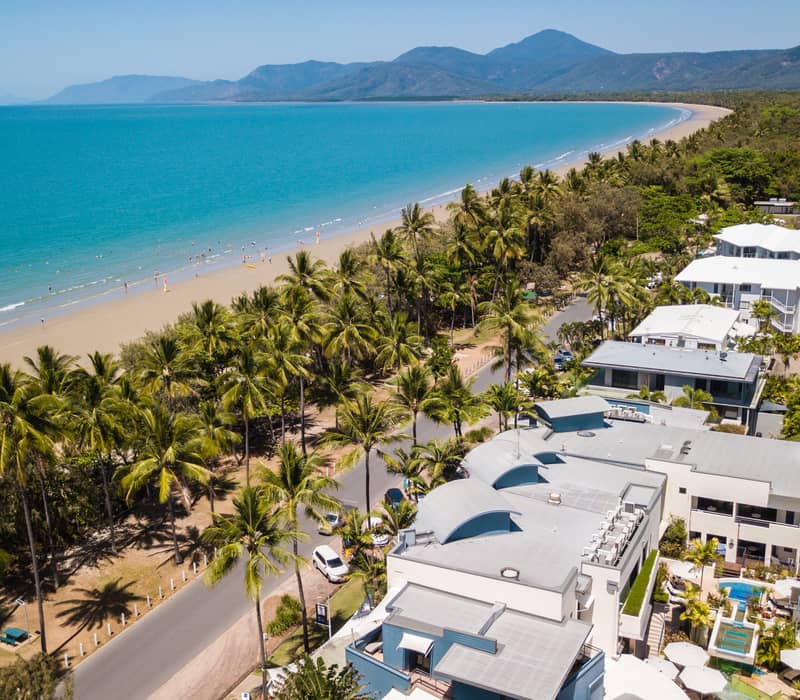 Modern boutique hotel bedroom with a king bed, timber headboard, and blue louvered windows in Port Douglas.