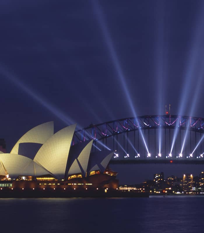 Sydney Opera House and Harbour Bridge illuminated at night.