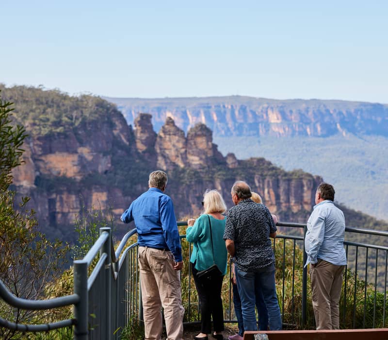 A group of people at a lookout fence viewing the Three Sisters in the Blue Mountains National Park.
