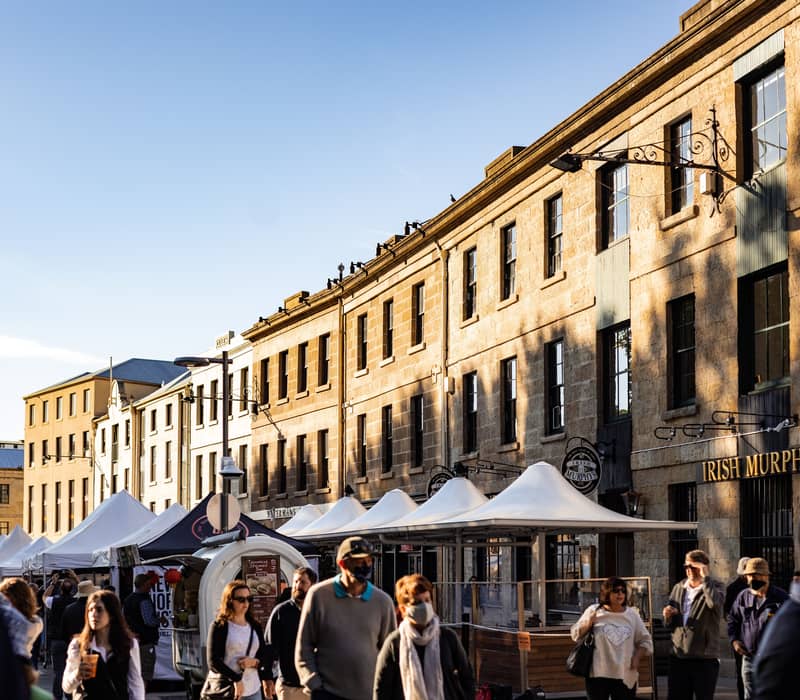 Visitors walking through the vibrant Salamanca Market stalls in Hobart, Tasmania.