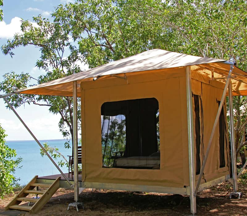 A luxury safari tent interior with wooden beds and views of the Australian bush.