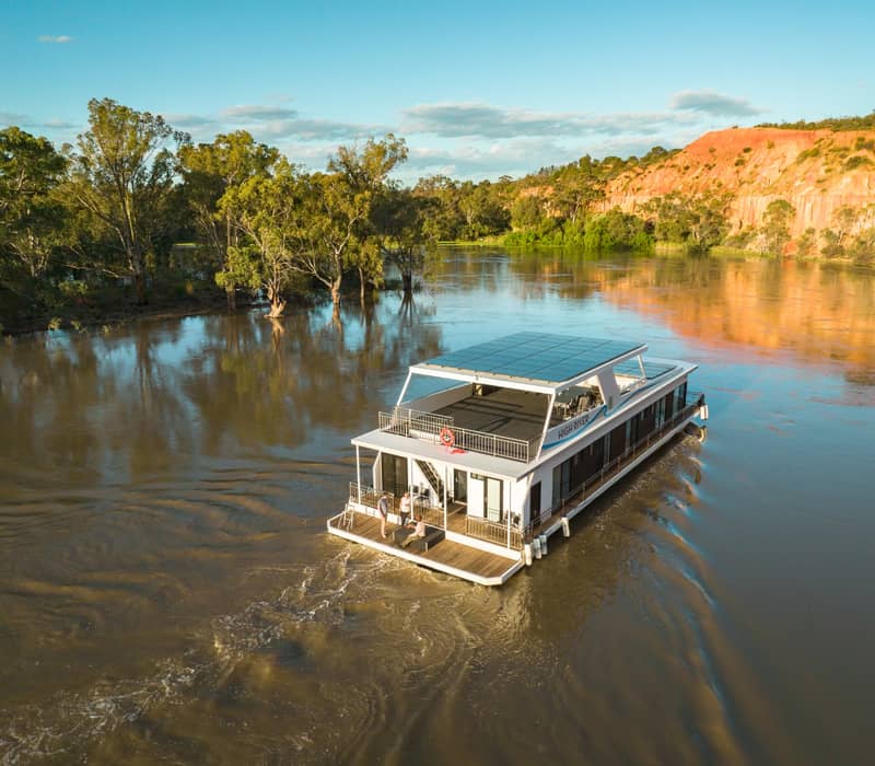 A modern hot tub on a houseboat deck with views of the Murray River and red cliffs.