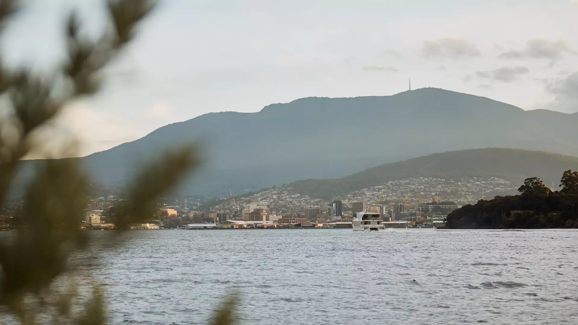 The Hobart city skyline and Mount Wellington seen across the water at dusk.