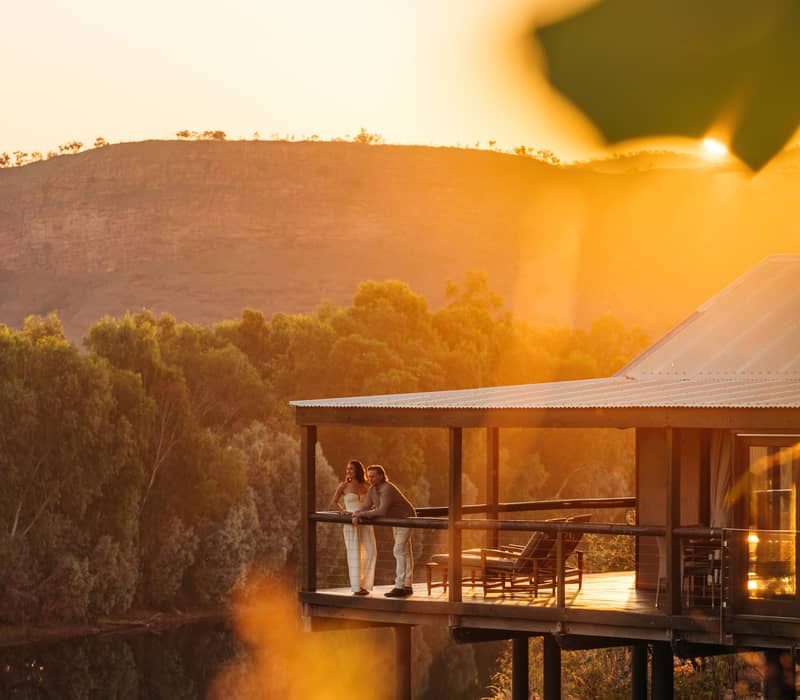 Luxury outback lodge balcony at sunset overlooking a river and cliffs in the East Kimberley, Western Australia.