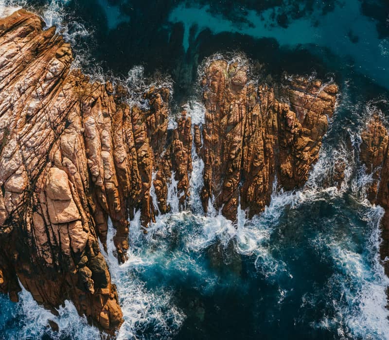 A stunning top-down aerial shot shows the white wash of the Indian Ocean surging through the narrow granite channels of Canal Rocks near Yallingup in the Margaret River region.