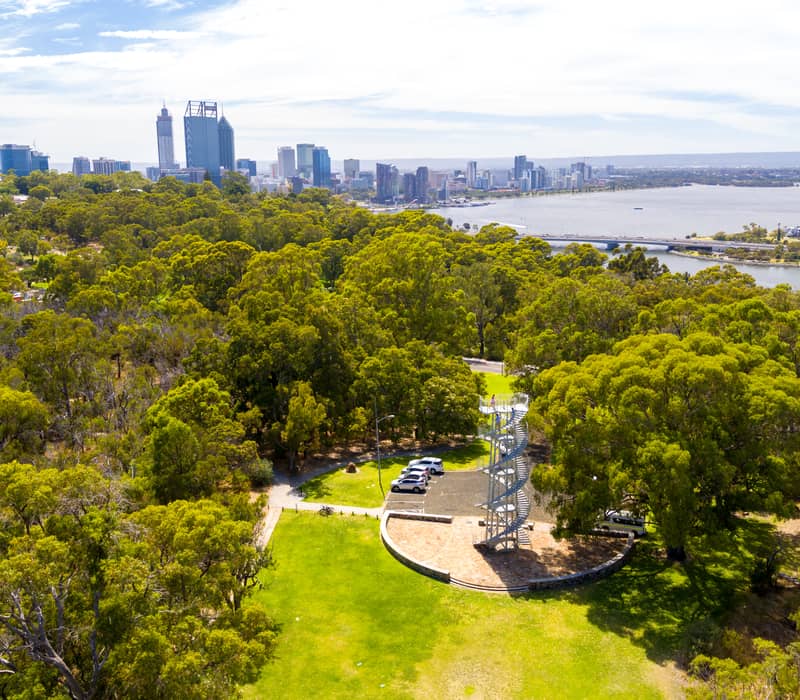 Aerial view of DNA Tower in Kings Park Perth with city skyscrapers and river under a blue sky.