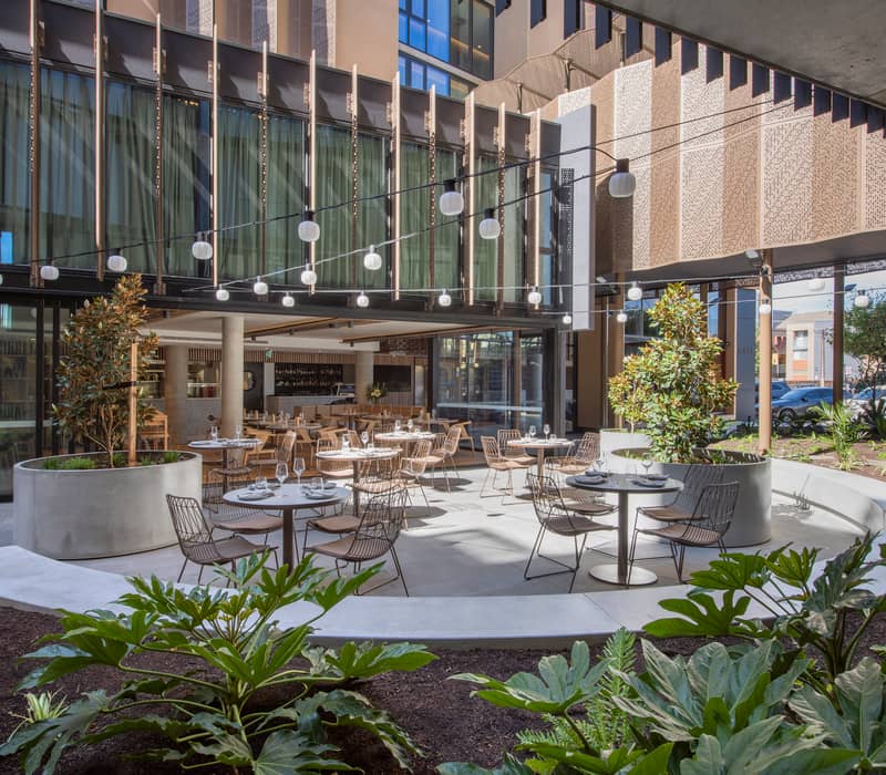 Modern hotel bedroom with timber accents and floor-to-ceiling windows at Vibe Hotel Adelaide.