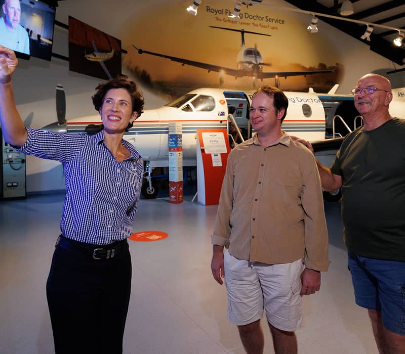 A staff member explaining an interactive screen to visitors at the RFDS Darwin museum.