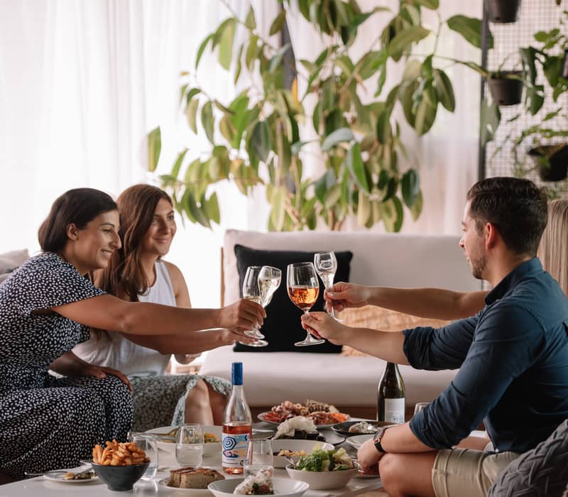 A group of four friends toast with glasses of sparkling wine in a modern lounge at Brown Brothers.