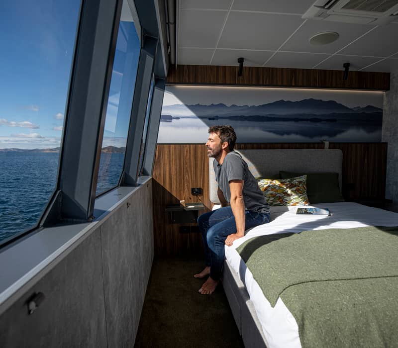 A luxury cabin featuring massive picture windows offers immersive coastal views on an On Board Expedition Cruise in Tasmania.