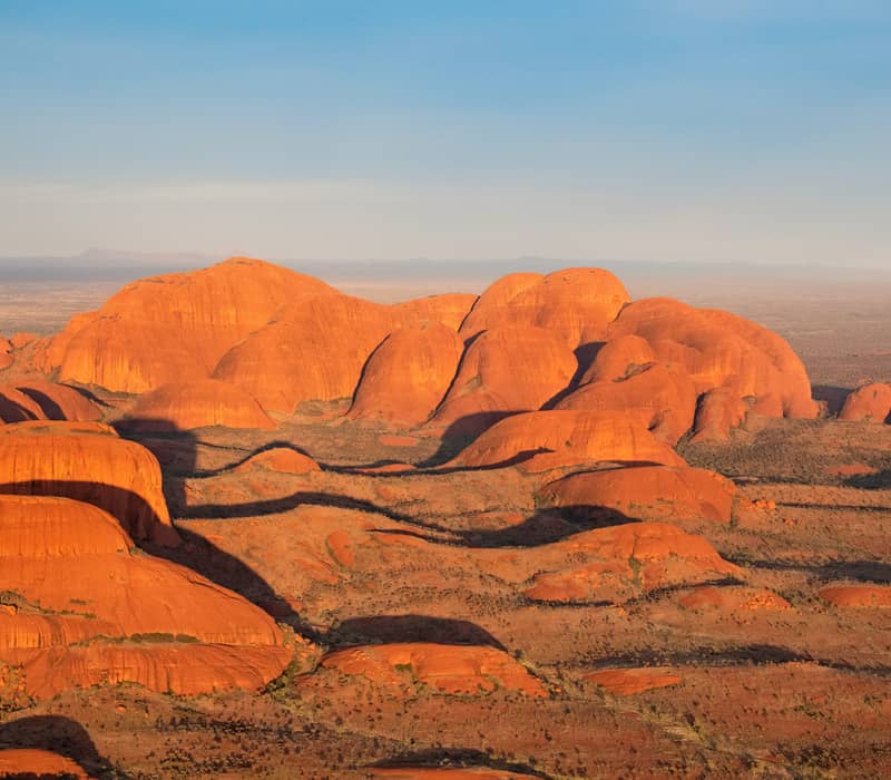 High-angle scenic shot of the red rock domes of Kata Tjuta during sunset in the Red Centre.