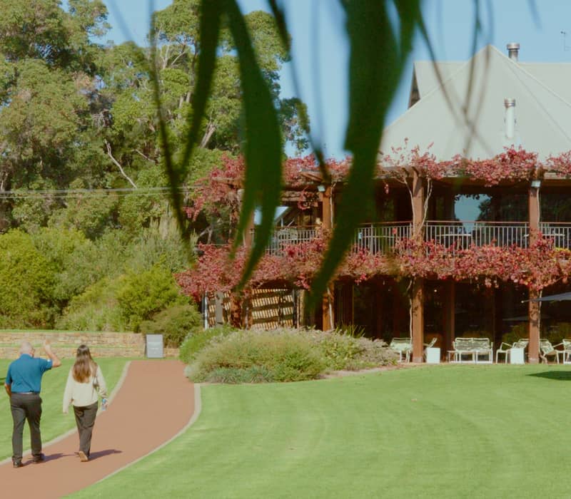 Two people walking on a red path towards a large, vine-covered winery building under a clear blue sky.
LIMITED - only to be used when promoting operator