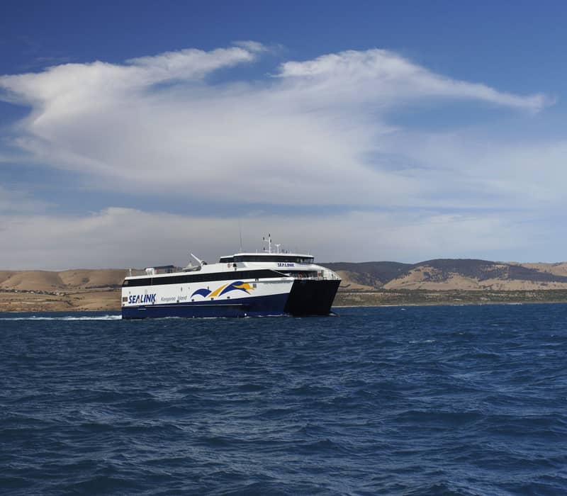 A SeaLink ferry navigating the coastal waters near hilly terrain on the way to Kangaroo Island.